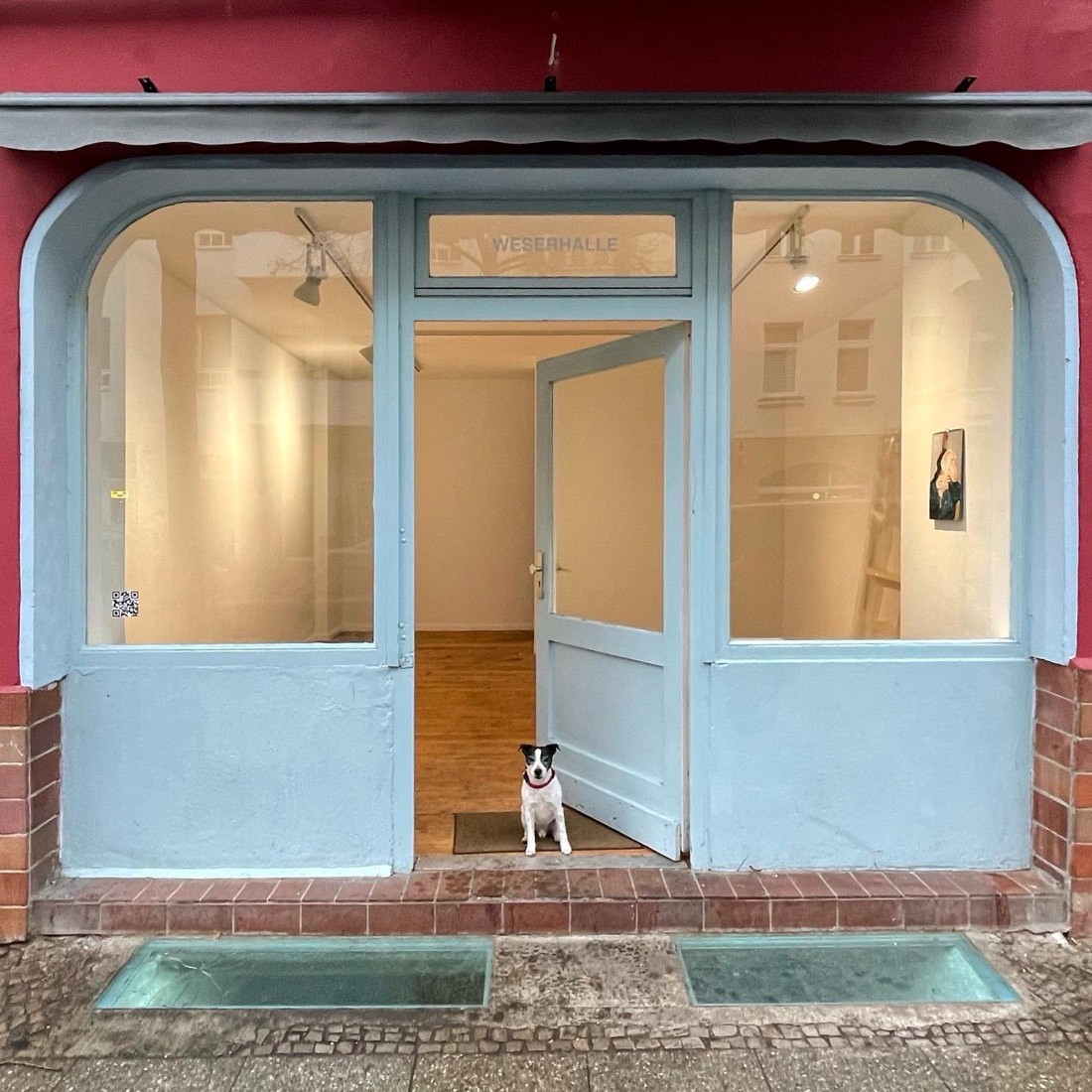 Weserhalle’s shopfront on Weserstraße: the door open, Cushti the dog sitting on the threshold